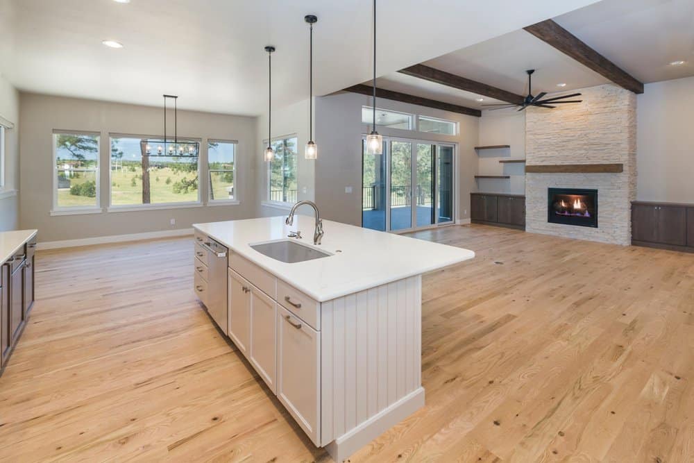 Tour Homes That Fit Your Needs Bright open-concept kitchen and living room with a fireplace and large windows.