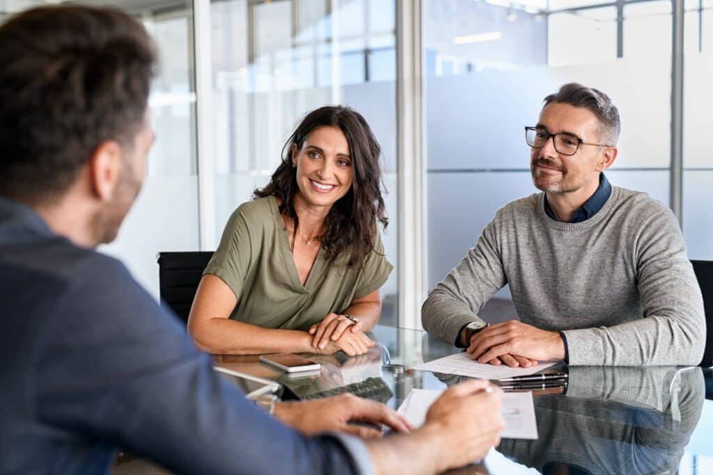 Meeting With Your Real Estate Agent A couple meeting with a real estate agent across a conference table for an initial home buying consultation, reviewing documents together